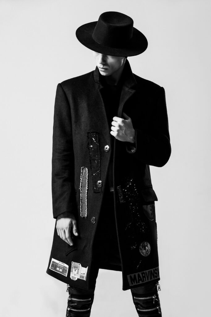 Stylish man in black outfit and wide-brim hat striking a pose.